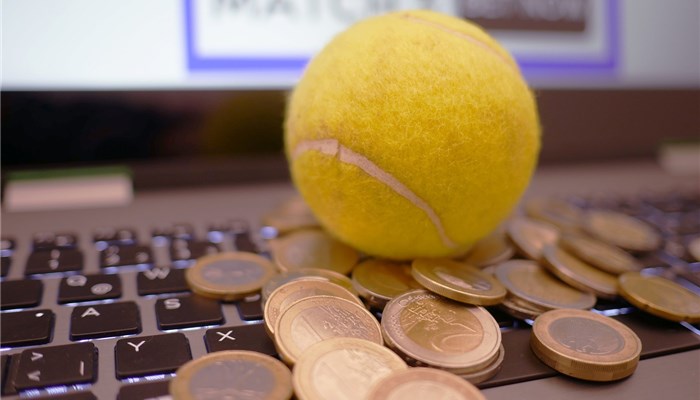 ノートパソコンの上にテニスボールとコインが乗っている