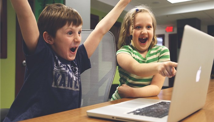 子供二人がパソコンの前で喜んでいる